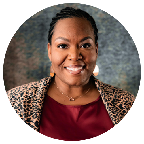 A young Black woman with braids pulled back, wearing a sweater and smiling at the camera.